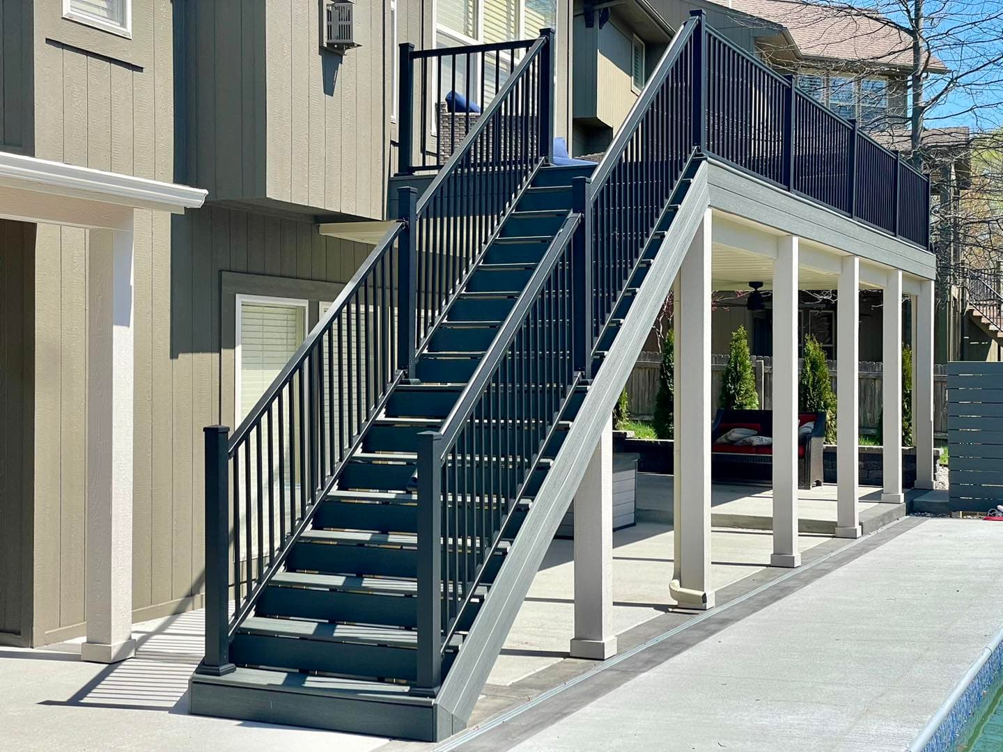 Outdoor black metal staircase leading to a second floor of a home, with a modern design.